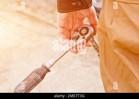 Uomo meccanico con cacciavite elettrico che sostituisce il pneumatico all'esterno. Servizio auto. Sostituire gli pneumatici sulle ruote con le mani. Concetto di installazione degli pneumatici Foto Stock