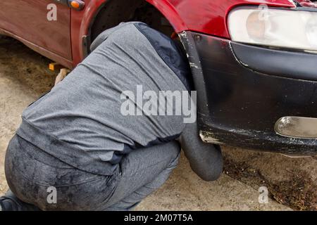 Processo di assistenza. Un uomo tiene uno pneumatico in garage. Sostituzione degli pneumatici invernali ed estivi. Concetto di sostituzione stagionale degli pneumatici Foto Stock