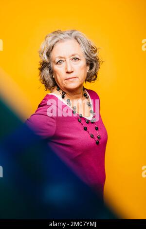 Ritratto di una donna anziana che indossa un maglione rosa su uno sfondo giallo Foto Stock