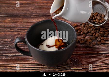 Espresso con gelato in tazza di porcellana nera su tavolo di legno. Caffè affogato Foto Stock