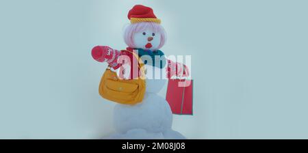 Moda divertente pupazzo di neve con la borsa dello shopping sullo sfondo neve all'aperto. Banner di Natale con pupazzo di neve alla moda. Biglietto di auguri di nuovo anno con Foto Stock