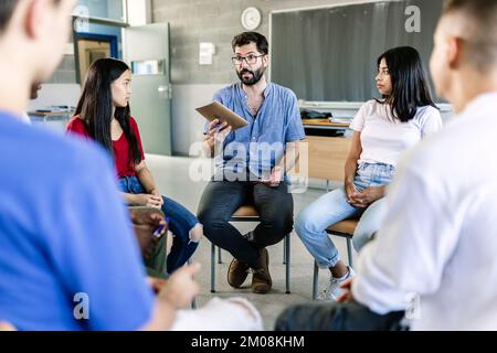 Diversi studenti delle scuole superiori che prendono con l'insegnante durante il gruppo di discussione Foto Stock