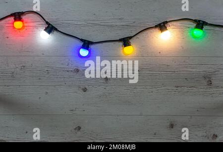 Lampade a colori garland su sfondo di legno chiaro curvato Foto Stock