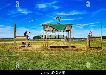 Grande tavolo con due sedie su un prato, passanti-facendo una pausa insieme, divertirsi, il tempo soleggiato, immagine simbolica del tour in bicicletta, pista ciclabile, Foto Stock