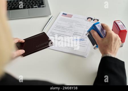 Primo piano del lavoratore dell'ufficio immigrazione che approva la domanda di visto per una giovane donna caucasica Foto Stock