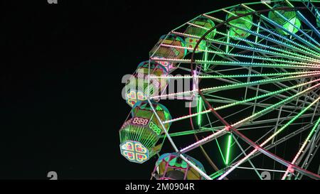 Ruota panoramica gigante con illuminazione verde in una fiera indiana Exhibition di notte Foto Stock