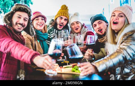 Giovani amici alla moda che brinda vino rosso al ristorante Garden out Side - concetto di stile di vita con persone felici miste che si divertono insieme al bar della cantina Foto Stock
