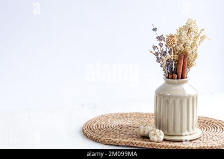 Vaso con fiori secchi e bastoncini di cannella isolati su fondo bianco. Foto Stock