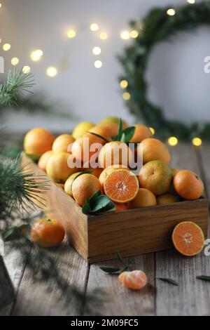 Tangerini in una scatola rettangolare di legno e rami di abete rosso su fondo di legno. Natale o Capodanno rustico ancora vita Foto Stock