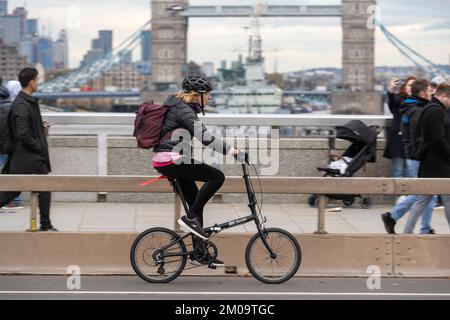 Una donna che si collega in bicicletta durante l'ora di punta attraverso il London Bridge, Londra, Regno Unito. 18 Nov 2022 Foto Stock