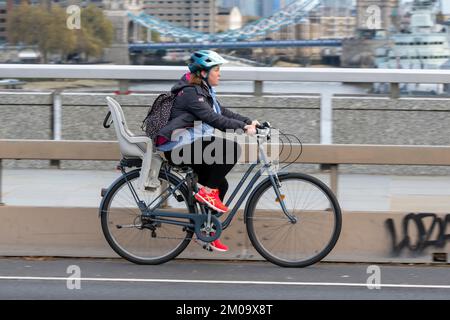 Una donna che si collega in bicicletta durante l'ora di punta attraverso il London Bridge, Londra, Regno Unito. 17 Nov 2022 Foto Stock