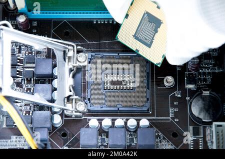 Vista dall'alto della scheda madre e del tecnico sull'inserimento del chip della CPU. Foto Stock