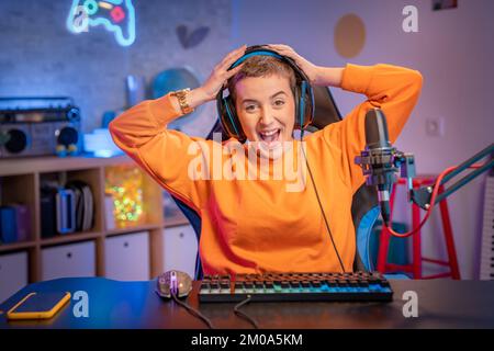 Ragazza entusiasta gamer in cuffia con un microfono che gioca Online Video Game sul suo Personal computer Foto Stock