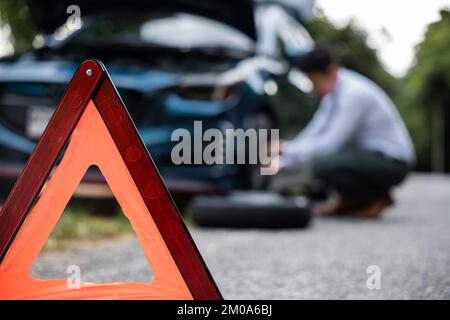 L'uomo d'affari asiatico auto rotta ha problemi con la ruota della sua auto Foto Stock