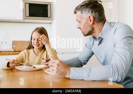 Il padre e la figlia mangiano insieme la colazione in cucina a casa Foto Stock