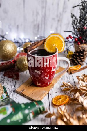 Uno shot verticale del VIN brulé di Natale in una tazza festosa con bastoncini di cannella e una fetta di limone Foto Stock