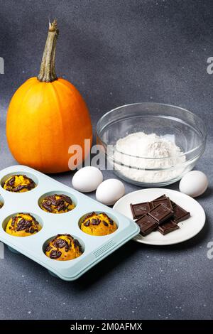 Muffin di zucca cotti al forno nella muffa di silicone al tavolo con ingredienti. Forno muffin sfondo cucina casalinga Foto Stock