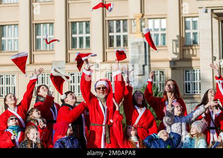 UZHHOROD, UCRAINA - 4 DICEMBRE 2022 - i volontari lanciano i loro cappelli di Babbo Natale in aria durante la parata di beneficenza degli aiutanti di San Nicola tenuta sotto Foto Stock
