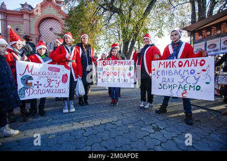 UZHHOROD, UCRAINA - 4 DICEMBRE 2022 - durante la parata di beneficenza degli aiutanti di San Nicola, i volontari vestiti in costume di Capodanno tengono cartelli Foto Stock