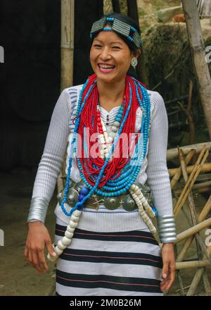 Raga, Arunachal Pradesh, India - 11 14 2010 : Ritratto all'aperto di una bella giovane donna sorridente della tribù Nyishi che indossa abiti tradizionali e gioielli Foto Stock