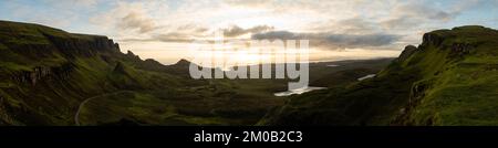 Foto panoramica di Quiraing sull'isola di Skye in Scozia sotto il cielo blu nuvoloso all'alba. Incredibile valle con colline coperte di erba Foto Stock