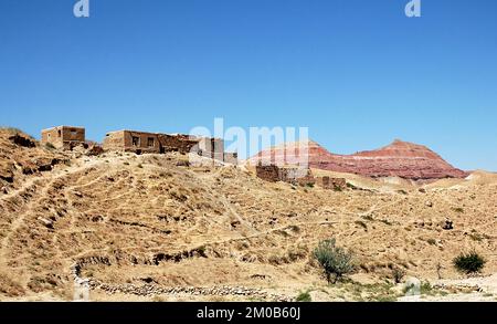 Villaggio tra Herat e Qala-e-Naw, provincia di Herat in Afghanistan con uno sfondo di colorate montagne rosse in una parte remota dell'Afghanistan occidentale. Foto Stock