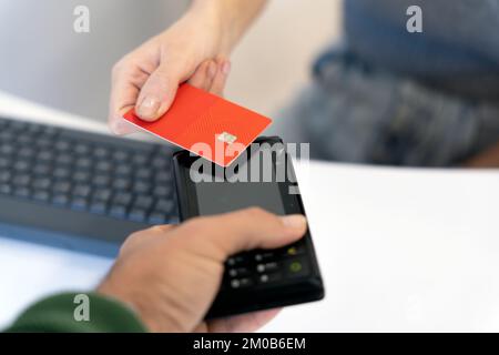 Dall'alto del raccolto irriconoscibile cliente femmina che utilizza la carta di credito mentre paga per l'acquisto contactless al cassiere maschio con terminale Foto Stock