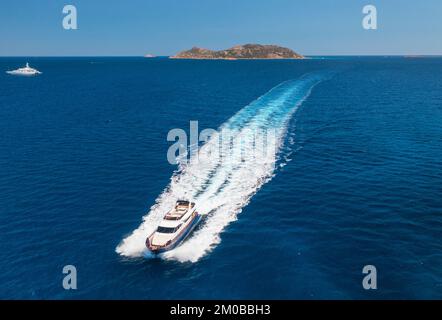 Vista aerea dello splendido yacht galleggiante di lusso nel mare blu al tramonto in estate. Isola Sardegna, Italia. Vista dall'alto del motoscafo, della costa del mare, trasparente Foto Stock