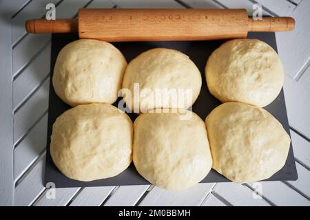 Matterello e palle di pasta su una tavola di legno, fuoco selettivo morbido. Palle di pasta con farina per pizza o torte e focaccine. Profondità di campo bassa. Foto di alta qualità Foto Stock