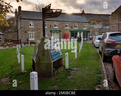 Mentre il sole tardivo inizia a tuffarsi dietro le colline, una vista frontale dei negozi Abbey e degli Abbey Tearooms. Rosedale Abbey. North Yorkshire Foto Stock