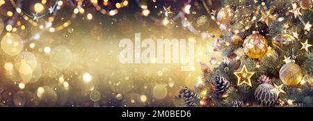 Albero di Natale dorato con Baubles in brillante sfondo festivo - ornamenti vintage su rami di abete con scintillanti e sfocate luci astrattate Foto Stock