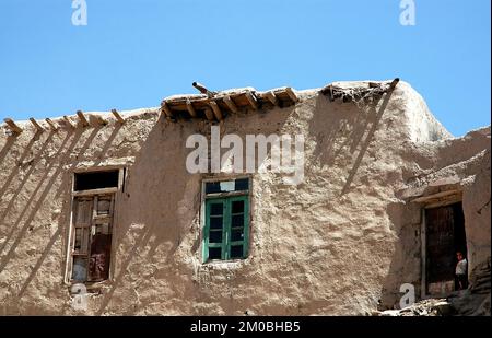 Ghazni / Afghanistan: Un piccolo bambino afghano guarda da una porta in una casa tradizionale a Ghazni. Foto Stock