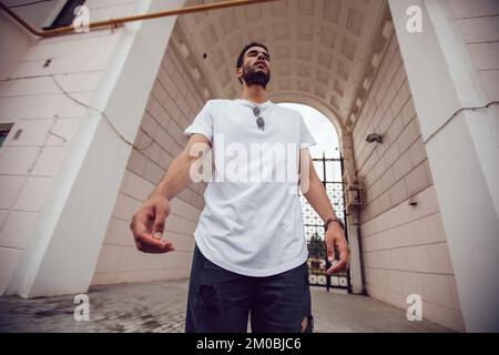 Un uomo afroamericano in una maglietta bianca passa per la strada. Simulazione. Foto Stock