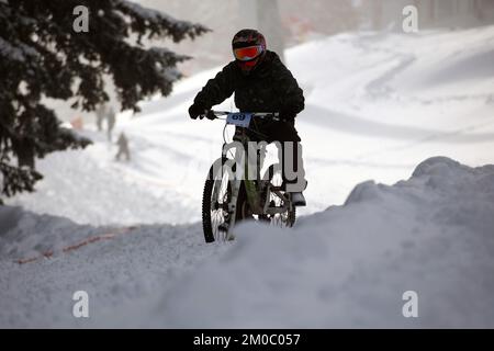 Sofia, Bulgaria - 22 gennaio 2022: Il ciclista percorre una discesa in bicicletta durante una gara estrema di mountain bike sulla neve sul monte Vitosha. Foto Stock