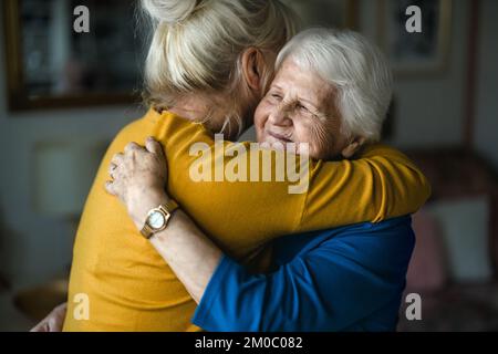 Donna che abbraccia la madre anziana Foto Stock