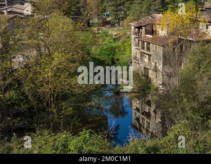 Vista di una casa medievale in una città vecchia in Catalogna con il fiume sottostante che riflette la casa circondata da vegetazione Foto Stock