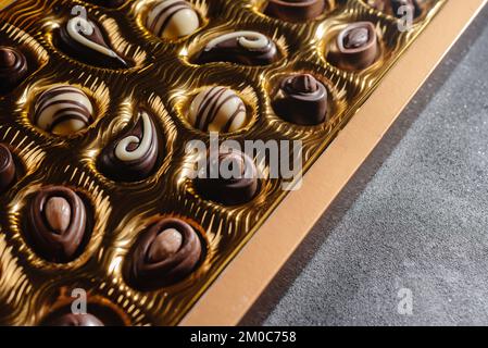 Una scatola di cioccolatini diversi. Assortimento di cioccolato sul tavolo nero, vista dall'alto Foto Stock