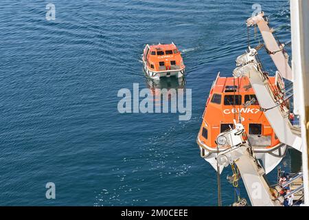 Argostili, Grecia - 2022 giugno: Scialuppa di salvataggio in discesa da una nave da crociera per portare i passeggeri a riva per visitare la città e l'area circostante Foto Stock