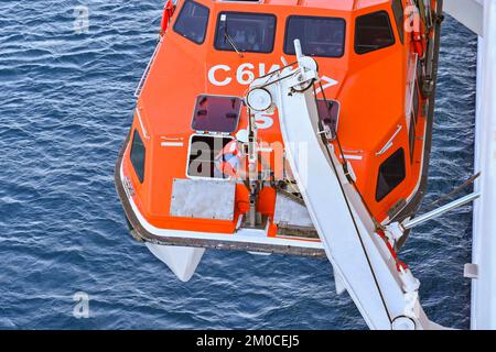 Argostili, Grecia - 2022 giugno: Membro dell'equipaggio che lavora su una scialuppa di salvataggio per abbassare la nave da crociera per portare i passeggeri a terra per visitare la città Foto Stock