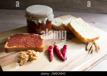 Pasta di pepe in vaso e fetta di pane con pasta di pepe su tavola di legno. Foto Stock