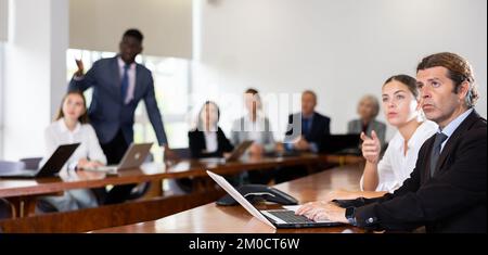 Uomo d'affari brunette bianco di media età che ascolta la presentazione Foto Stock