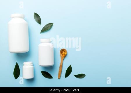Le capsule di Omega-3 si trovano in un flacone bianco su un tavolo con il fondo verde delle foglie. Compresse di olio di pesce. Additivi biologicamente attivi omega 6, omega 9, vitam Foto Stock