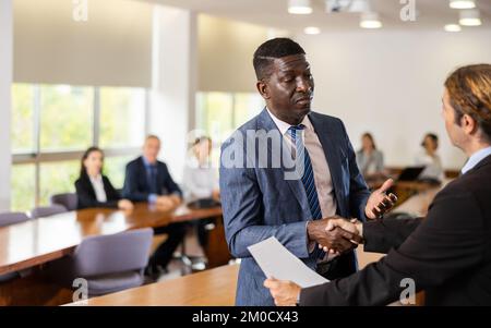 Uomini d'affari positivi handshaking dopo la firma del contratto Foto Stock