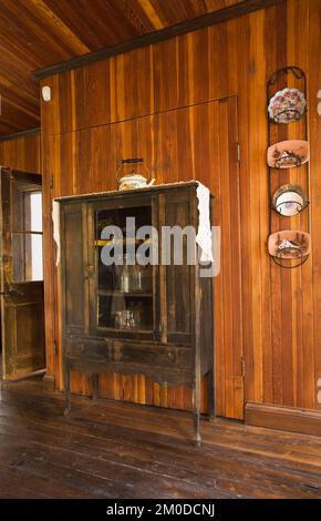 Armadietto in legno antico e vetro con vecchie bottiglie di latte in cucina all'interno di una vecchia casa in stile cottage canadese del 1826. Foto Stock