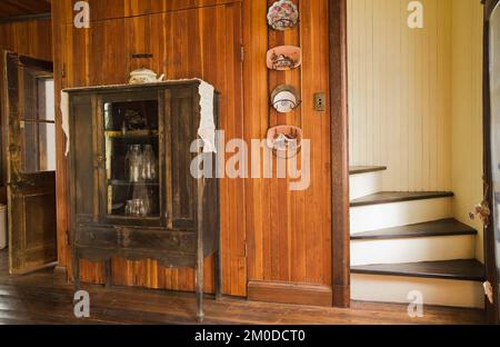 Armadietto antico con vecchie bottiglie di latte in cucina all'interno di una vecchia casa in stile cottage canadese del 1826. Foto Stock