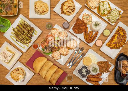 Un set di piatti con ricette colombiane e venezuelane, con un sacco di plantane, empanadas, pesce alla griglia e arepas assortiti Foto Stock