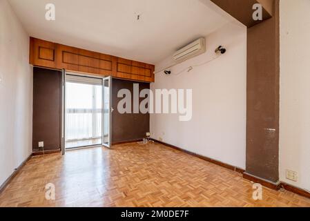 Soggiorno vuoto di una casa con pavimento in parquet di quercia a scacchiera e pareti dipinte in bianco e marrone scuro combinati Foto Stock