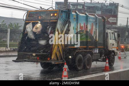 Ratchaburi, Thailandia, 14 2022 NOVEMBRE, Un camion dei rifiuti guida sotto la pioggia sulla strada in città Foto Stock