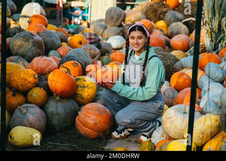 La donna contadina in una tuta di denim sceglie la zucca matura Foto Stock