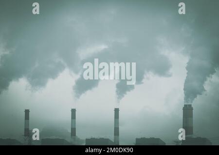 Colpo corto di centrale di carbone con vapore che fuoriesce dalla pila. Camino industriale di fumo della centrale a carbone al mattino. Foto Stock